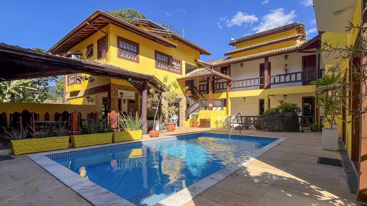 Exterior da Pousada Cicerone com piscina e fachada amarela